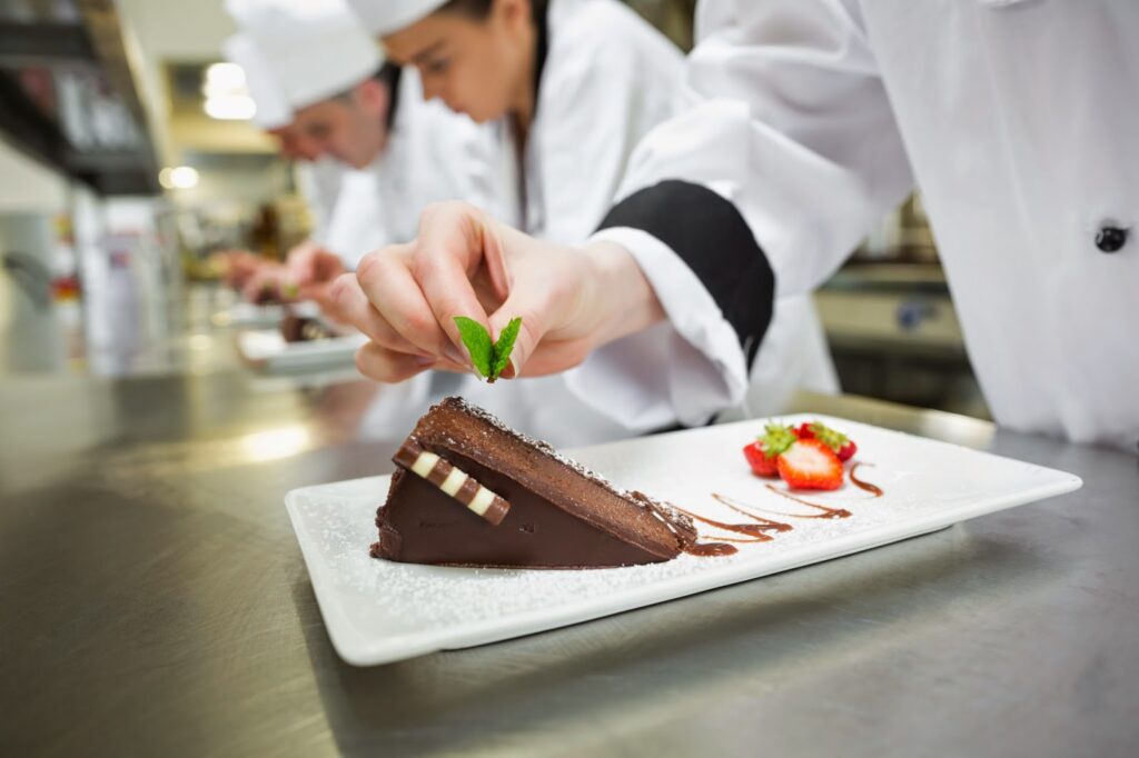 close up of chef putting mint leaf on chocholate cake